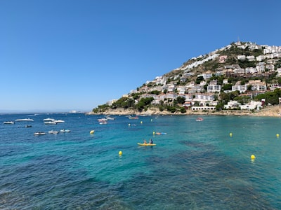 houses and building near mountain viewing blue sea during daytime roses teams background