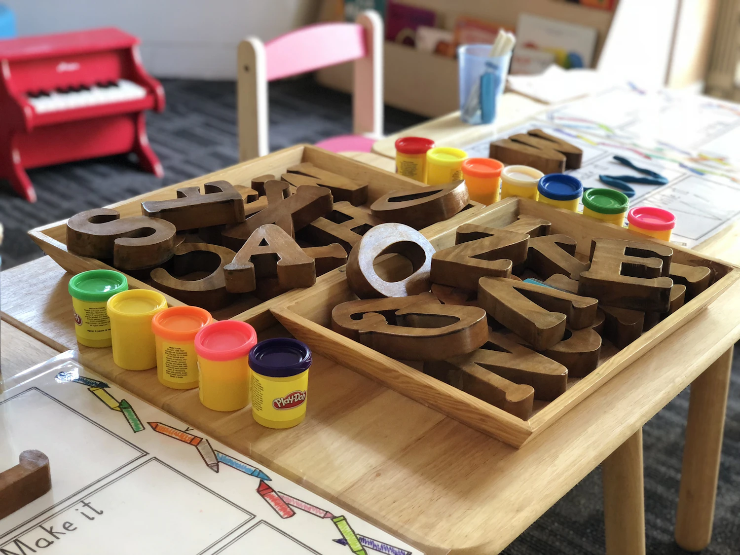 A preschooler pointing to and identifying colorful foam letters spread on a table
