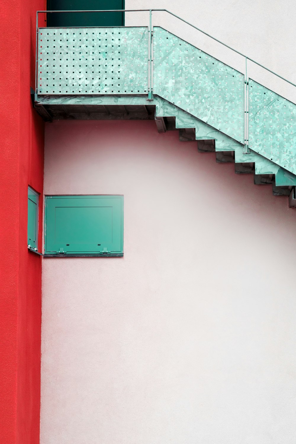 a red building with a green door and a stair case