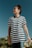 A person is wearing a black and white striped shirt with the word 'freedom' printed on it. They are standing outdoors under a clear blue sky, looking upwards with a calm expression. There are palm trees in the background.