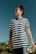 A person is wearing a black and white striped shirt with the word 'freedom' printed on it. They are standing outdoors under a clear blue sky, looking upwards with a calm expression. There are palm trees in the background.