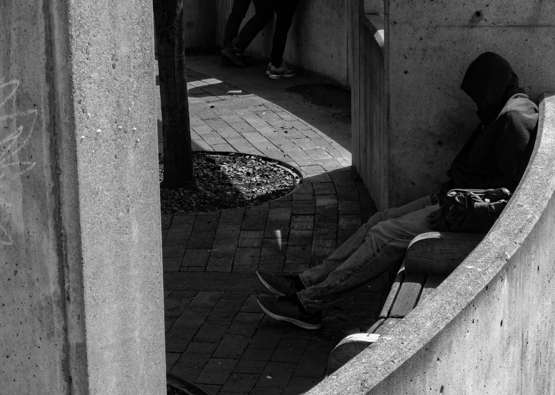 grayscale photography of man sitting on bench