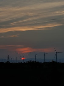 A powerful image of a wind farm against a sunset backdrop.