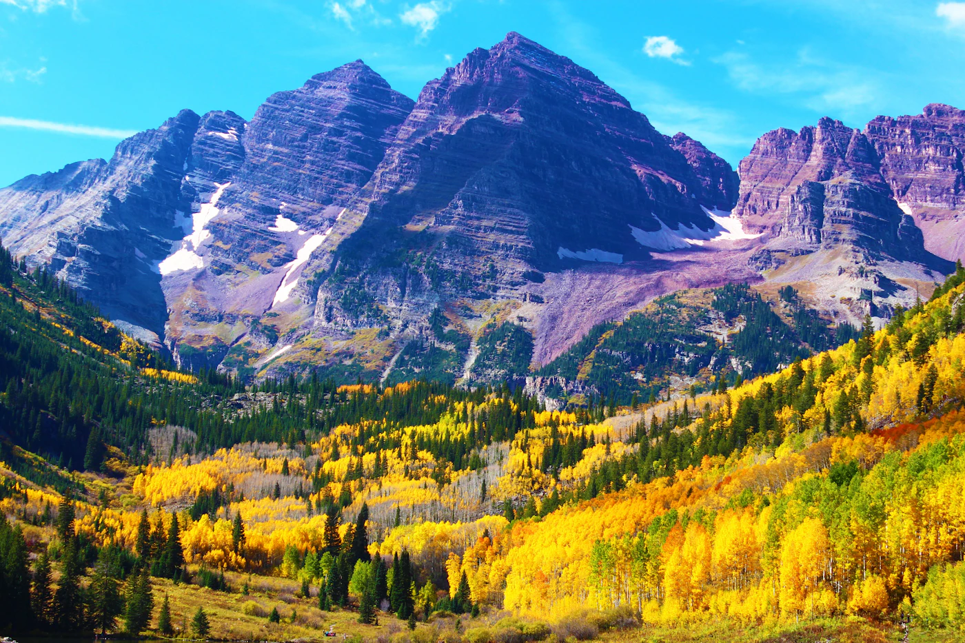 The Maroon Bells peaks above green aspen trees near Aspen, Colorado