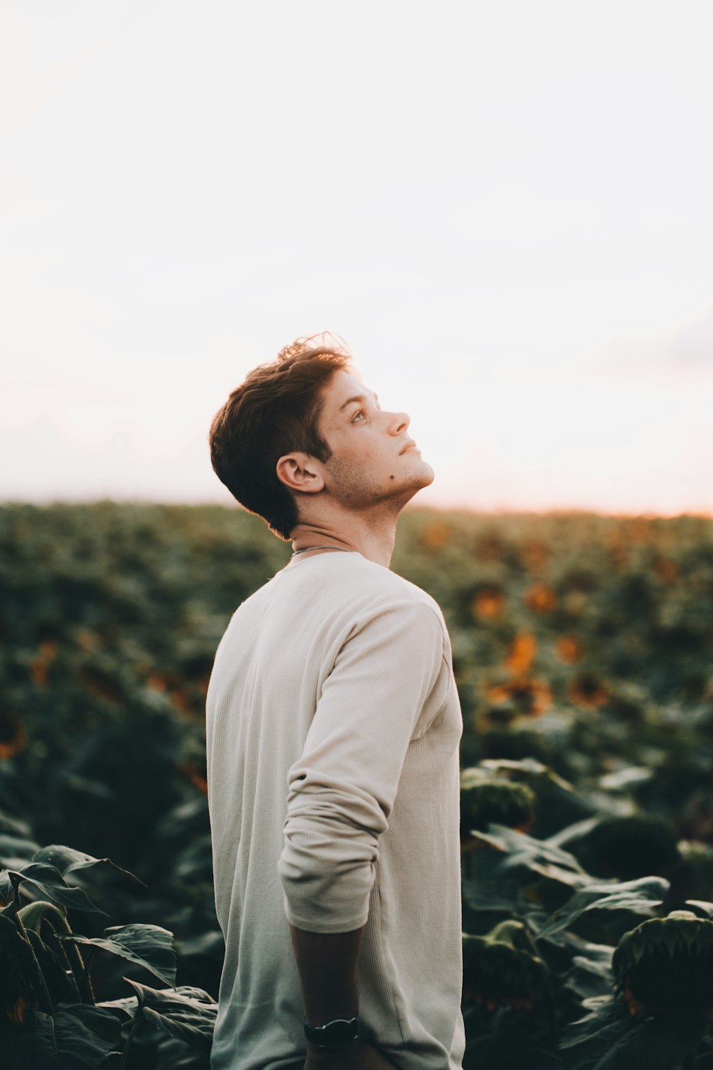 man wearing white crew-neck long-sleeved shirt standing and looking up