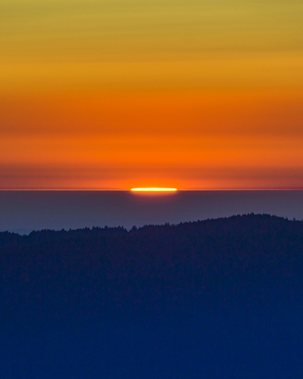 the sun is setting over a mountain range