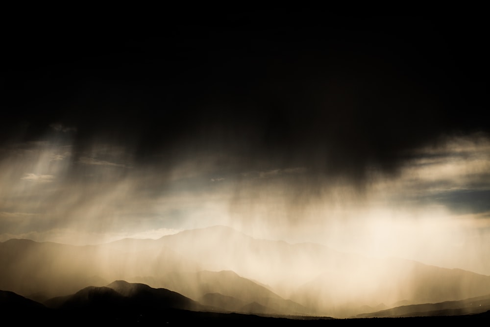 a black and white photo of a storm moving through the sky