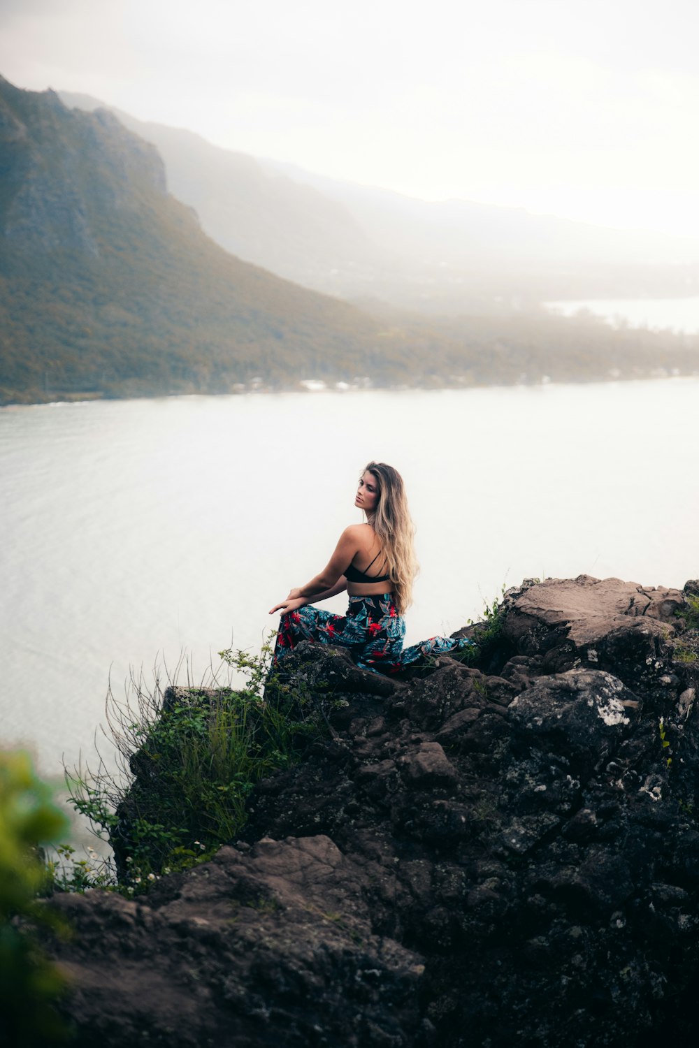 woman sitting on rock formation beside sea