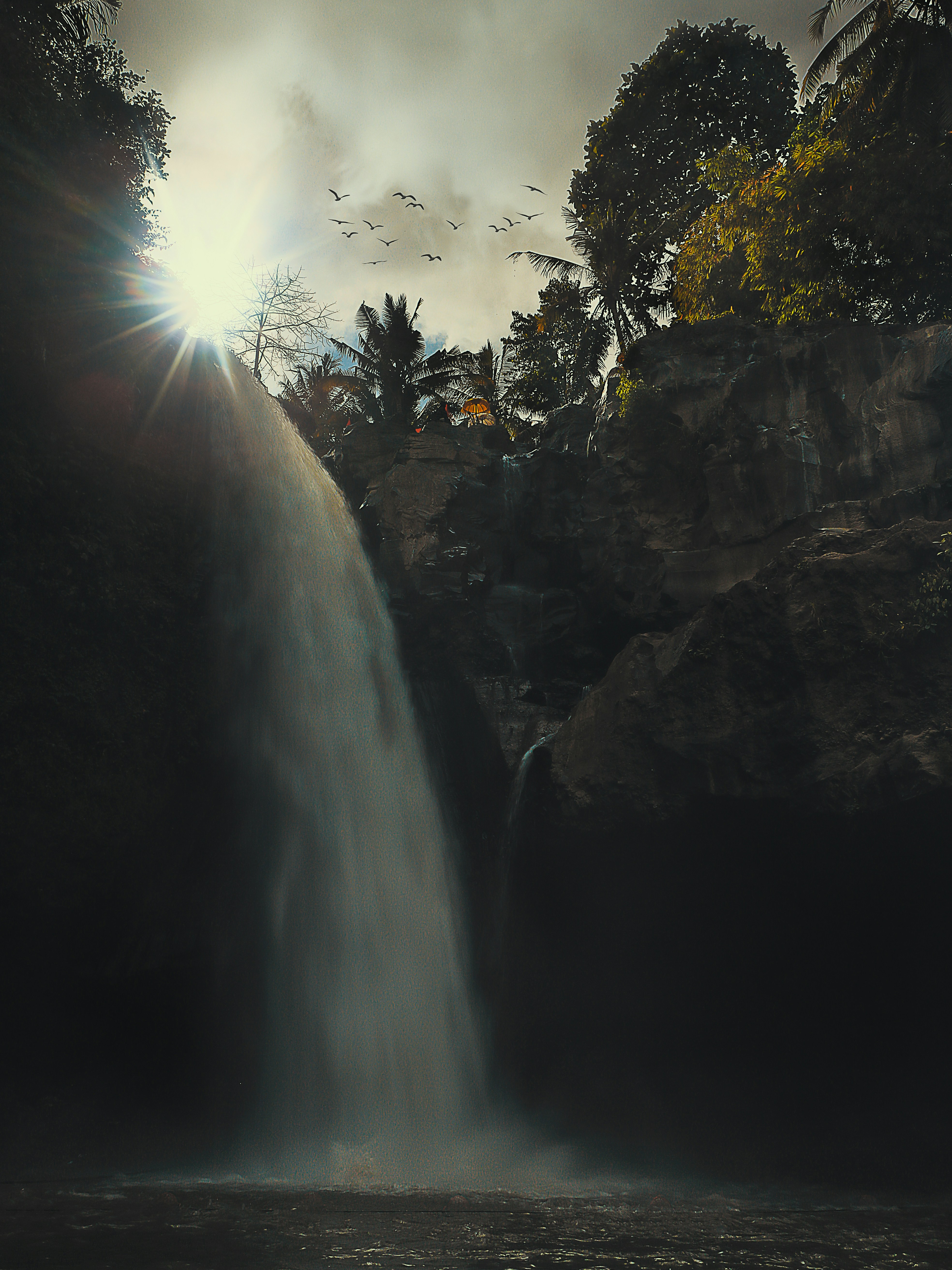 a large waterfall with birds flying over it