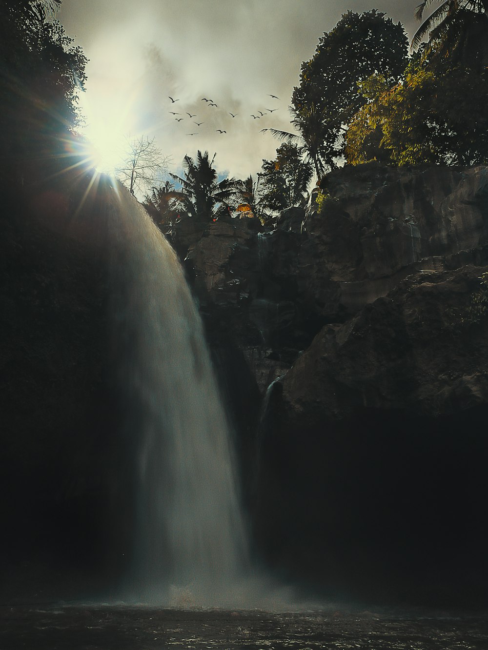 a large waterfall with birds flying over it