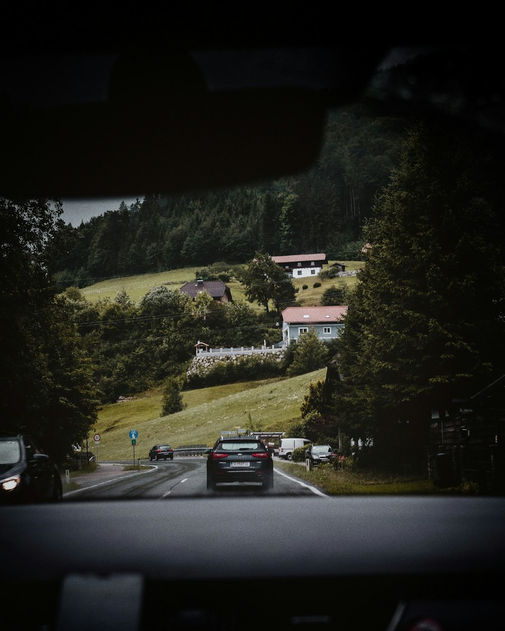 vehicles on road near trees and houses