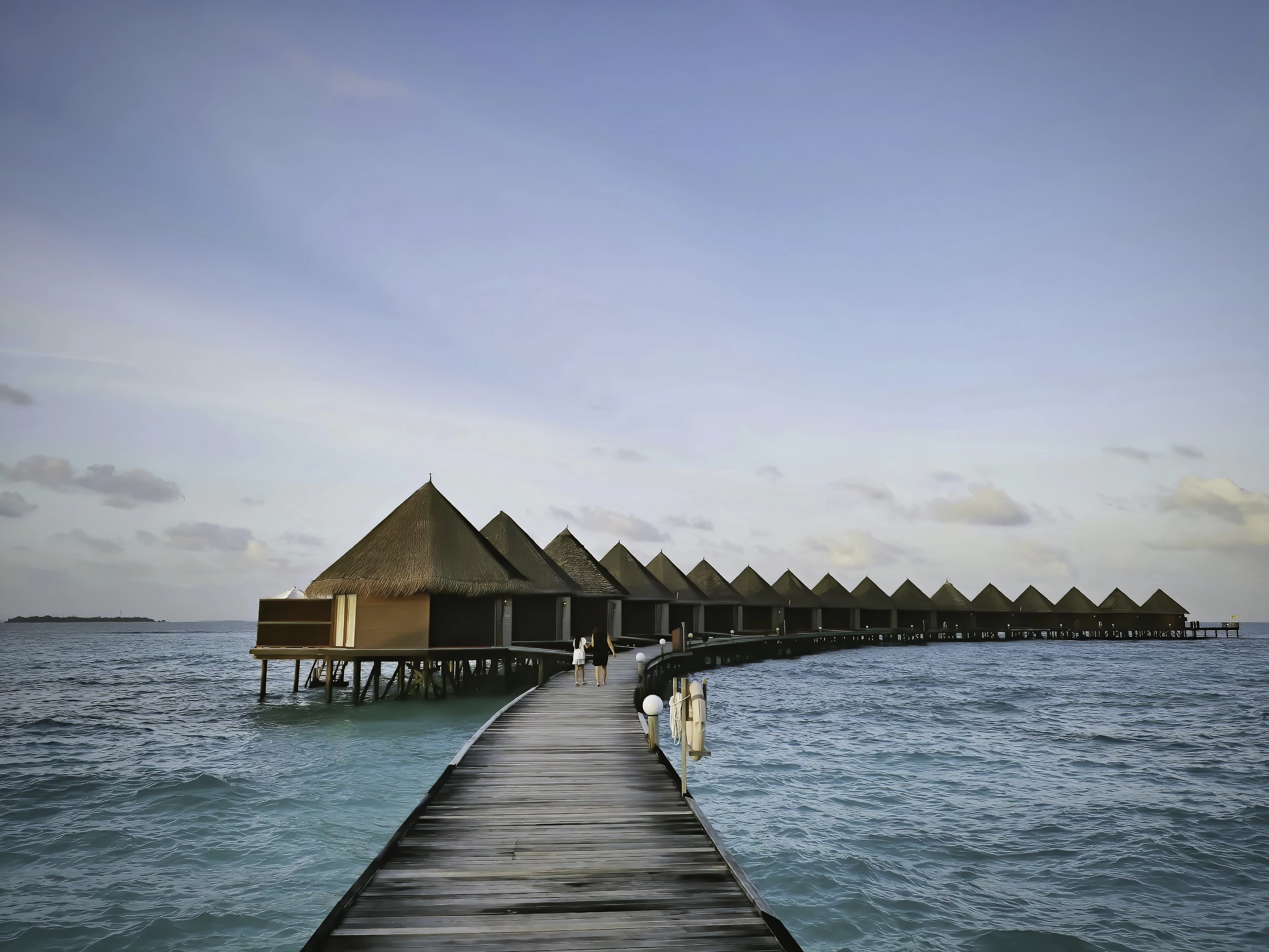 Two people walking along a jetty at a Maldives resort