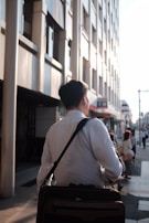 A casual tote bag slung over a shoulder, walking through a city street on a bright day.