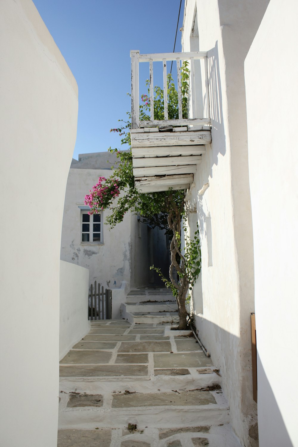 a white building with a wooden balcony and flowers