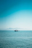 A serene view of the boat gliding over clear blue water with mountains in the background.