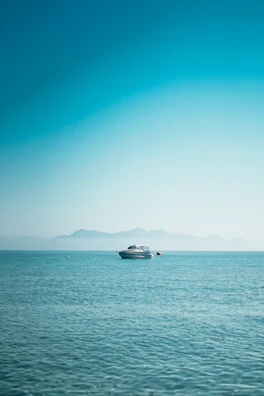 A serene view of the boat gliding over clear blue water with mountains in the background.