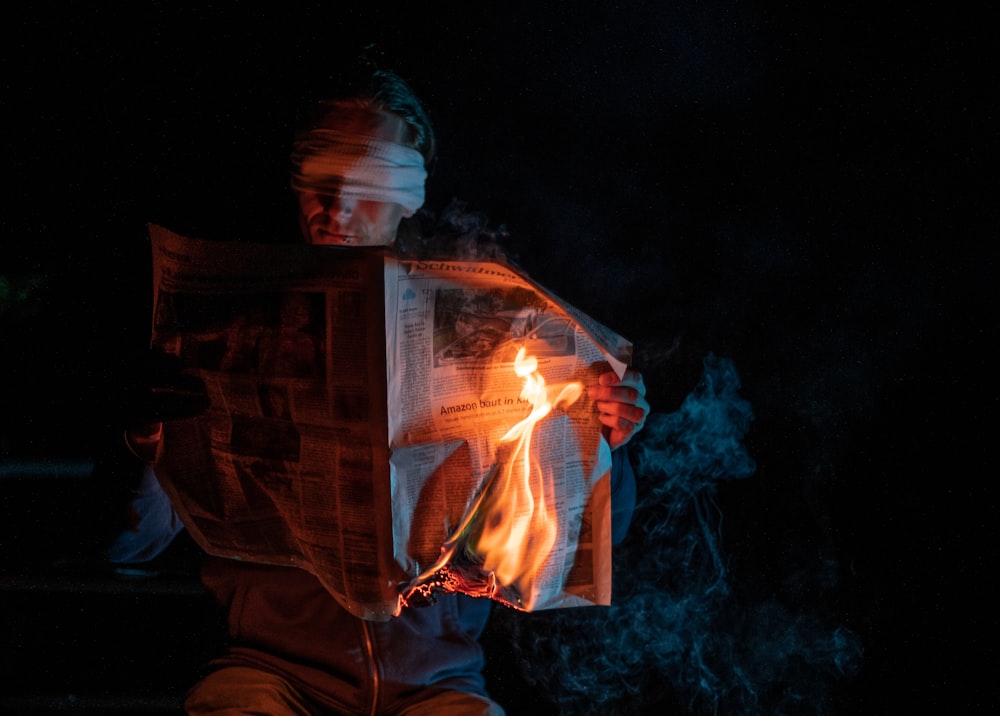 a man reading a newspaper while holding a fire
