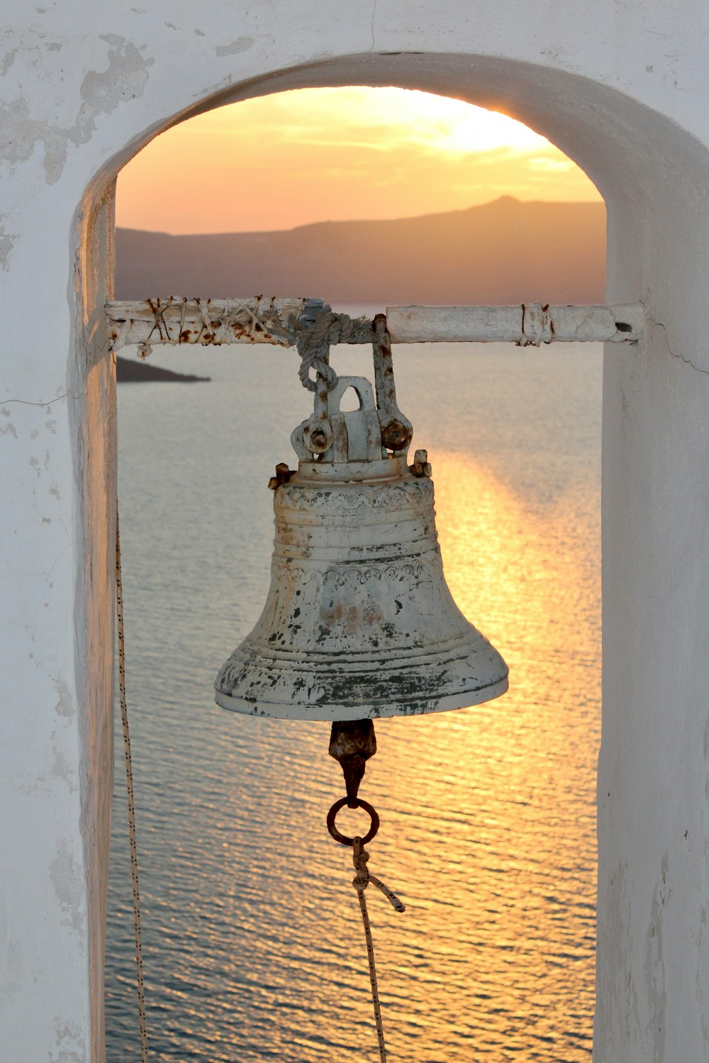 white and black metal bell near body of water