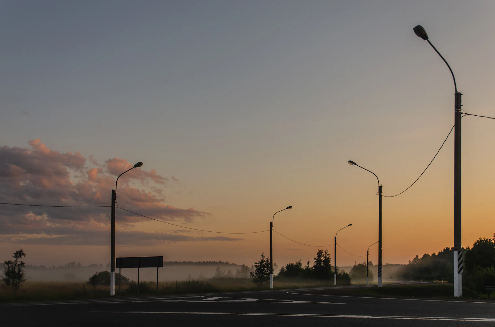 An empty two lane road stretching toward the horizon at golden hour