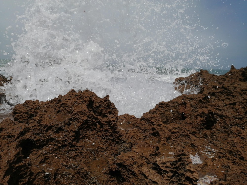 water splashing on brown rock