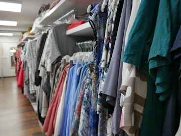 Rows of stylish apparel hanging on racks in a bright, organized wholesale store.