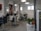 A modern hair salon interior with styling chairs, hair drying equipment, and large posters featuring hairstyles on the walls. There are potted plants adding a touch of greenery to the sleek and clean design. The room is well-lit with natural light coming through the windows and artificial ceiling lights.