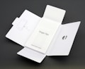 A Quick Start Guide titled 'Finger Tips' is placed in the center of an unfolded white cardboard package. The right side of the package has a cut-out opening, and the left side shows an illustration of a phone and a tool.