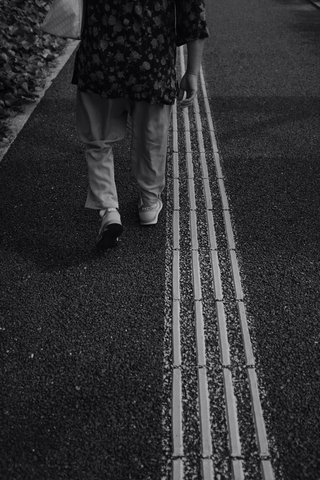 grayscale photography of person walking on pavement