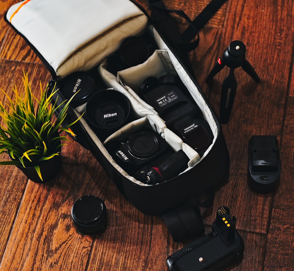 black DSLR camera with assorted accessories in black camera bag