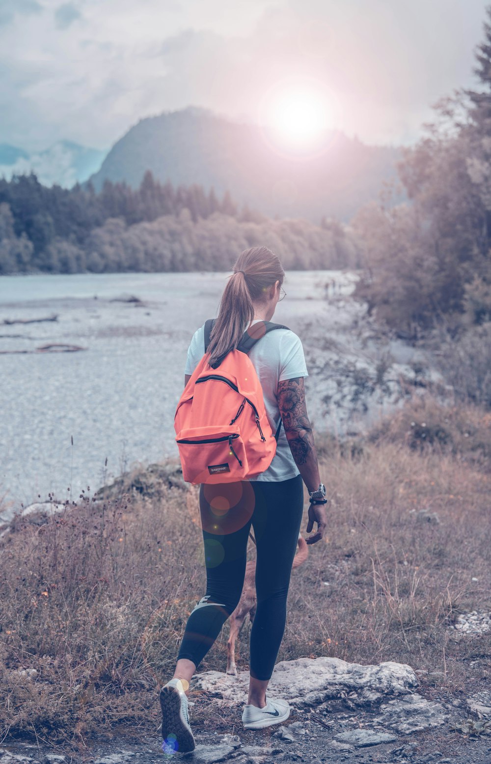 woman carrying orange leather backpack standing near body of water