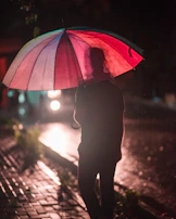 A chic striped umbrella open on a rainy city street, reflecting neon lights on wet pavement.