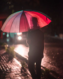 A chic striped umbrella open on a rainy city street, reflecting neon lights on wet pavement.