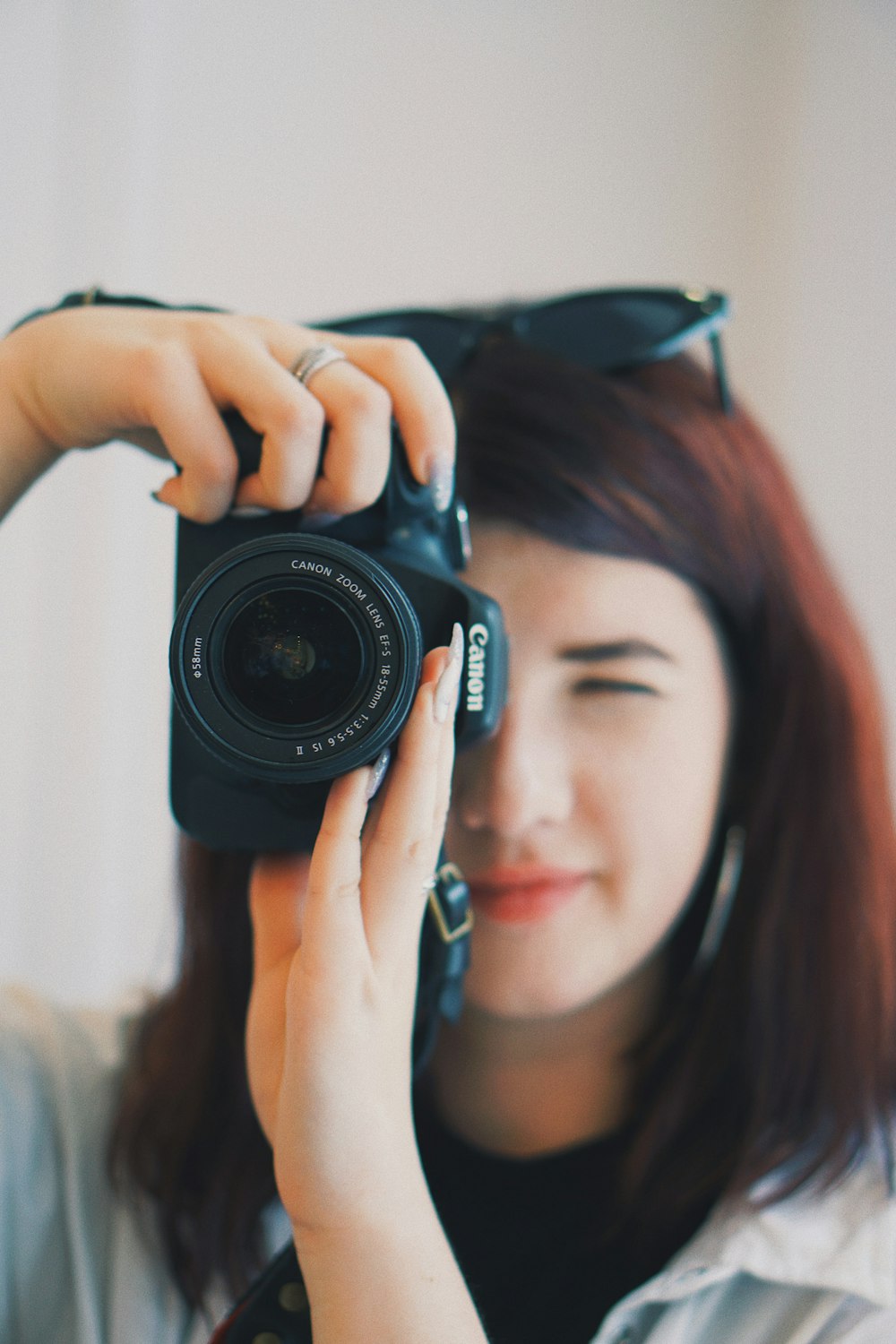 foto a fuoco superficiale di donna che utilizza una fotocamera reflex digitale Canon nera