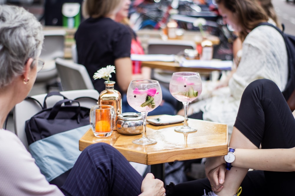 Un par de mujeres sentadas en una mesa con copas de vino