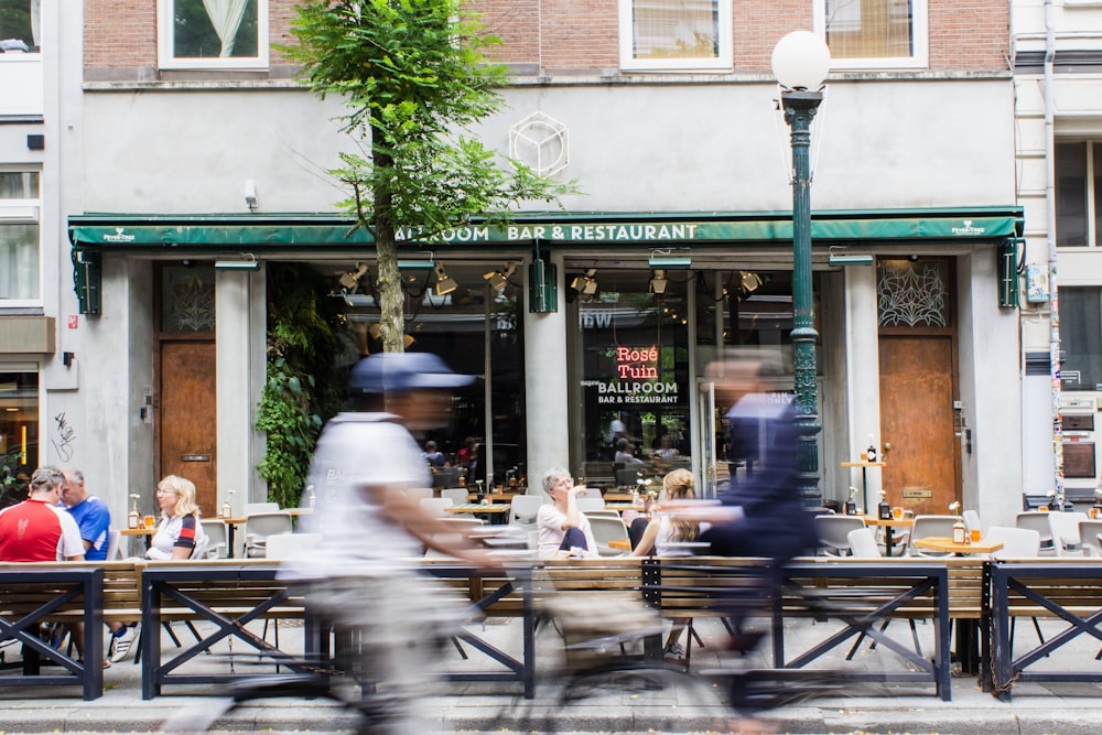 timelapse photo of person riding bike passing by storefront during daytime