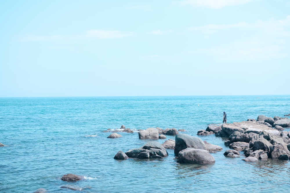 uomo in piedi sulla roccia vicino alla spiaggia