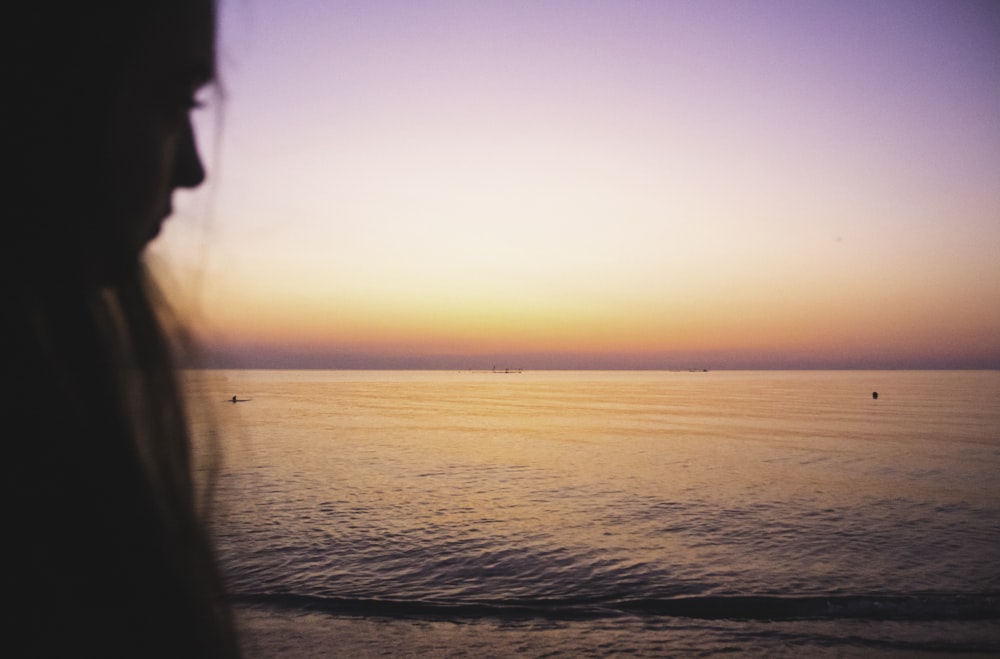 a woman standing in front of a body of water