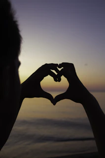 silhouette of person doing heart handsign