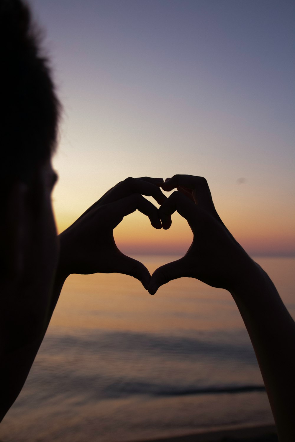silhouette of person doing heart handsign