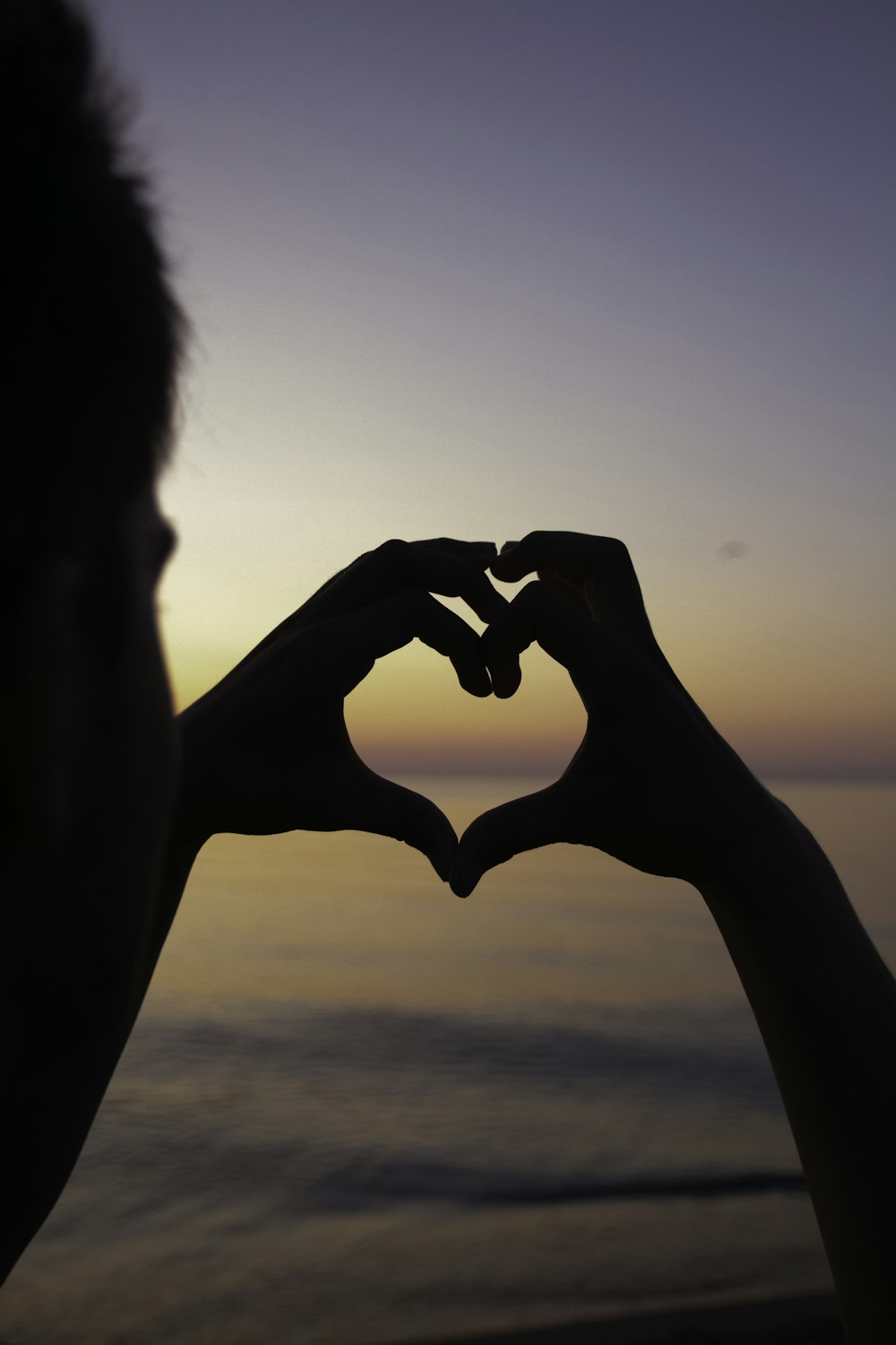 silhouette of person doing heart handsign