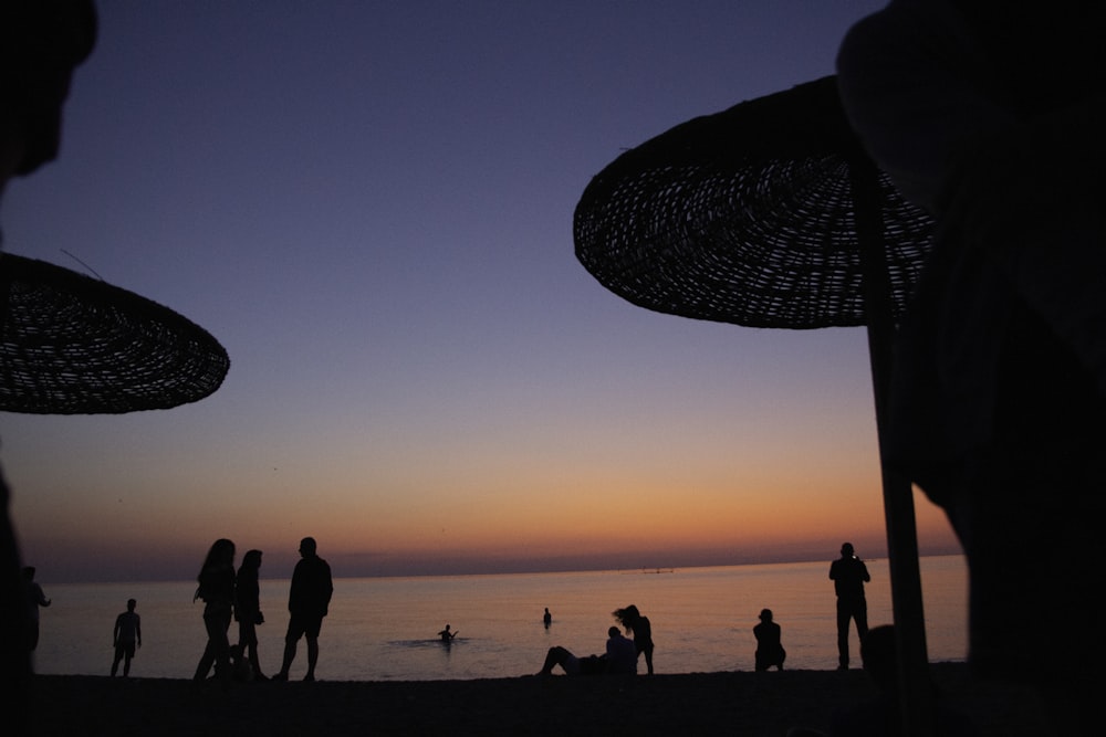 a group of people standing on top of a beach under umbrellas