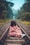 woman in pink floral short-sleeved dress sitting on train railing