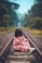 woman in pink floral short-sleeved dress sitting on train railing