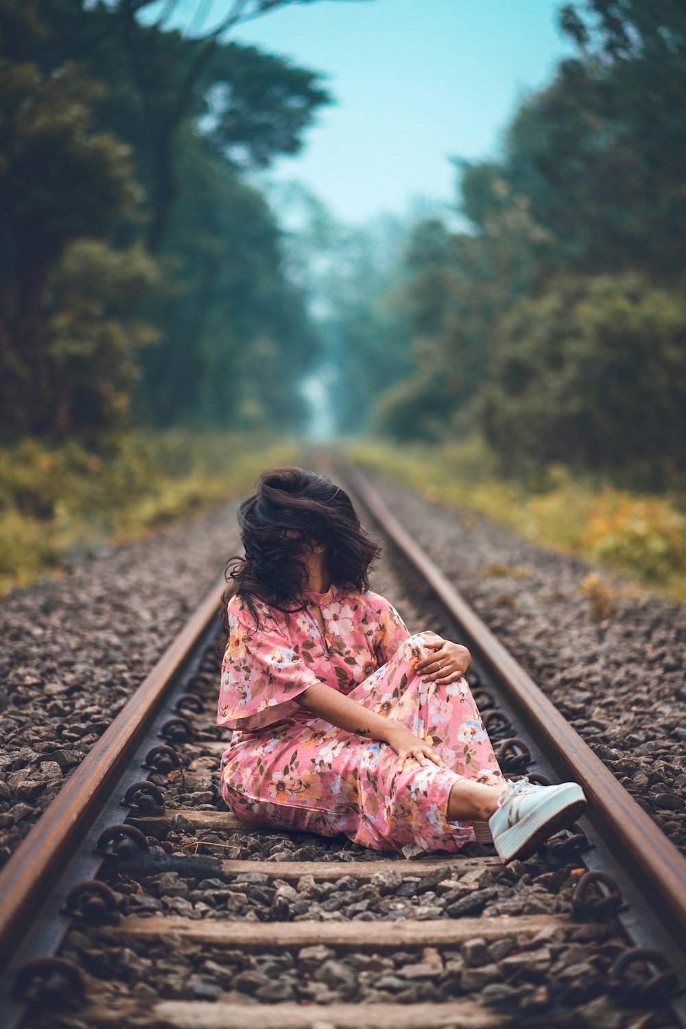 woman in pink floral short-sleeved dress sitting on train railing