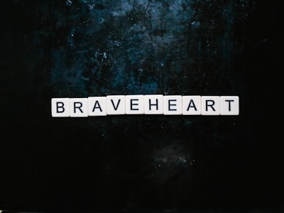 Letter tiles spell out the word 'BRAVEHEART' arranged neatly in a horizontal line against a dark, textured background.