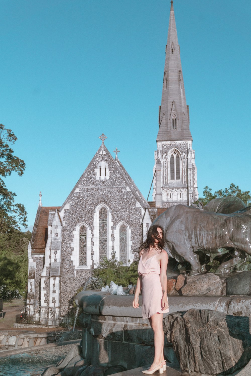 a woman standing in front of a fountain in front of a church