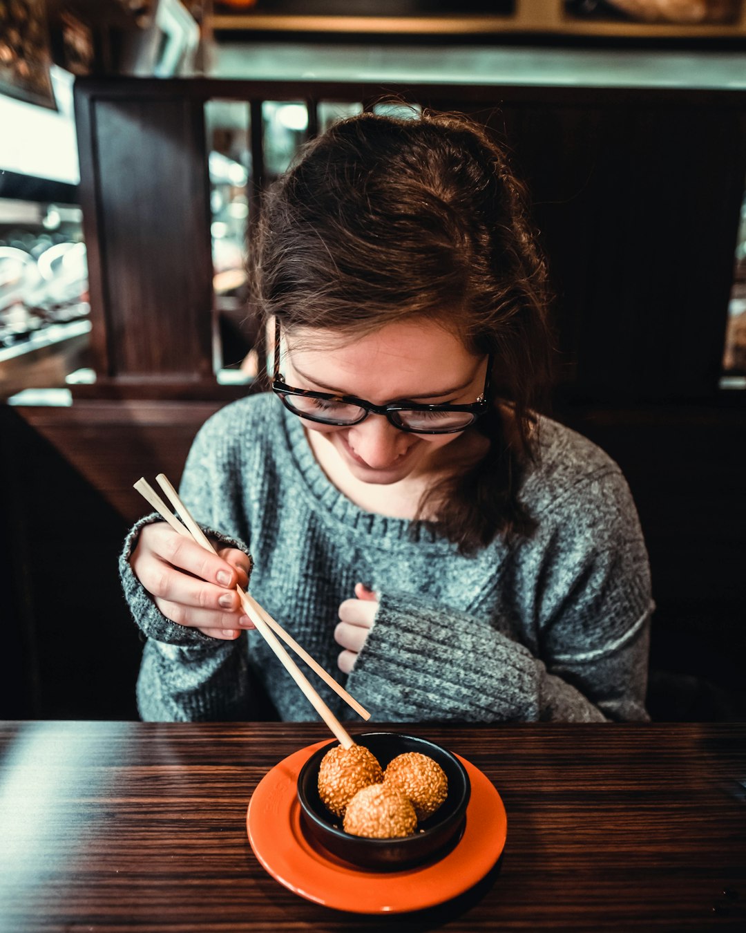 woman smiling while picking up food using chopstick