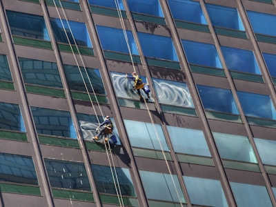 Technician performing high-altitude window cleaning on a tall building in Lanzarote.