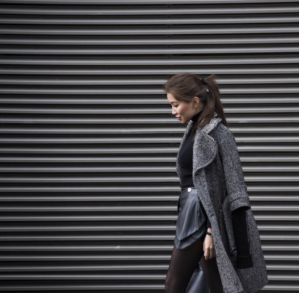 a woman walking down the street wearing a coat