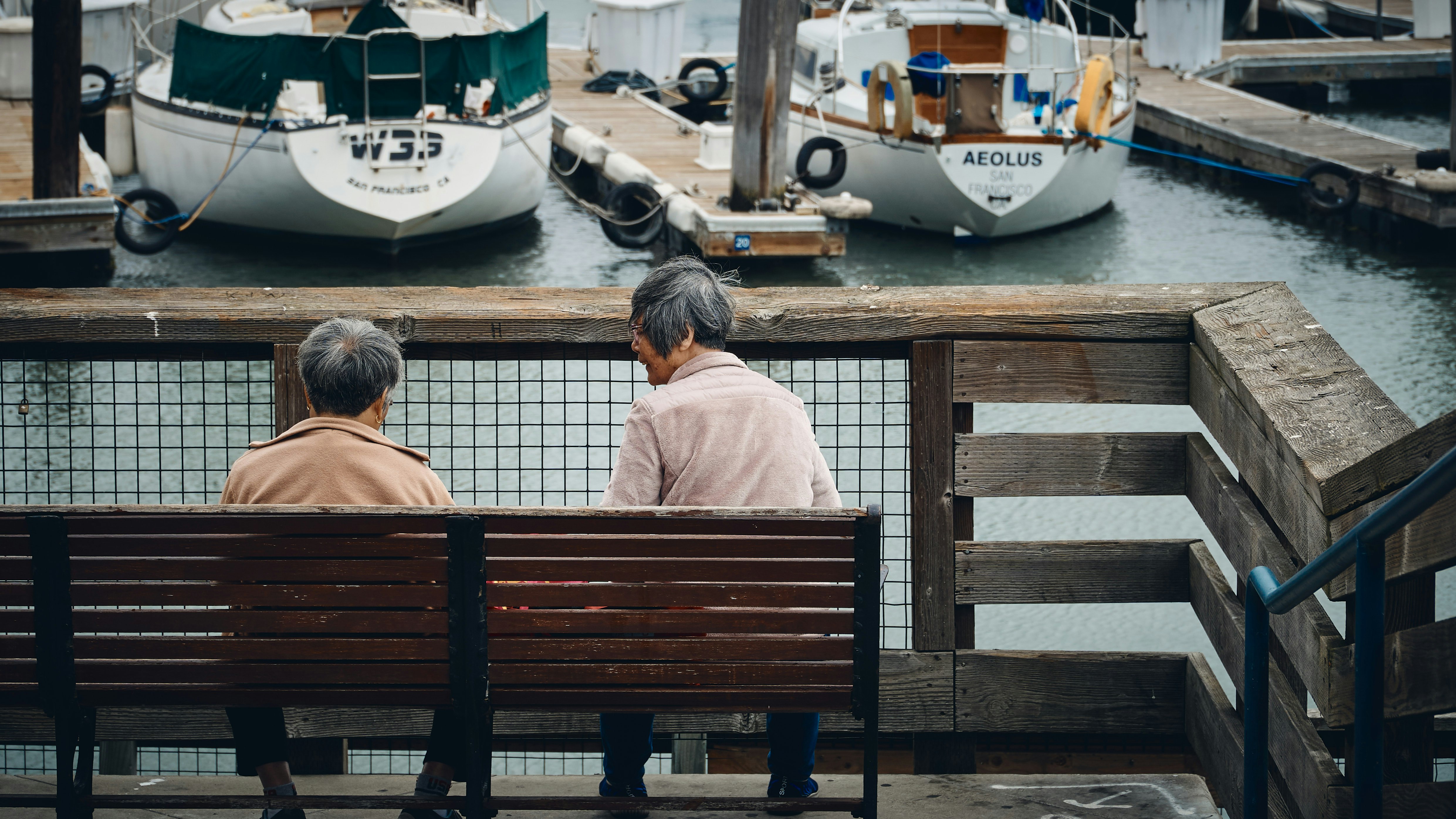 two person sitting in bench near boat during daytime